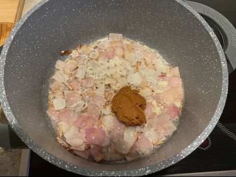 Rezept für eine Süßkartoffel-Kokos-Suppe: Gib die Curry-Paste mit in die Pfanne, sobald die Zwiebeln glasig sind.