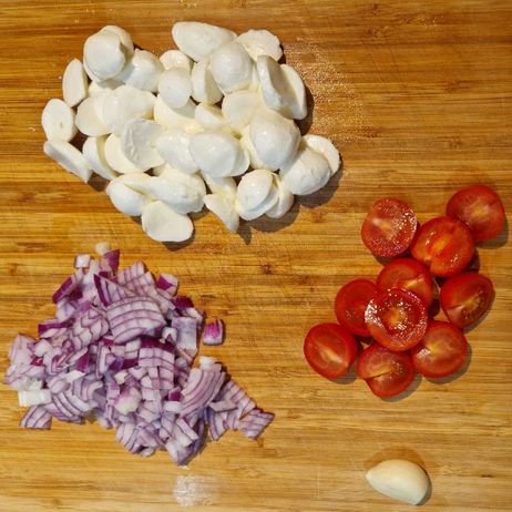 Gnocchi-Auflauf mit Blattspinat: Schneide die Tomaten, Zwiebeln und den Mozzarella in kleine Würfel bzw. Scheiben.