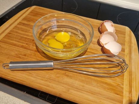 Rezept für ein paniertes Feta-Schnitzel mit Salat: Schlage die Eier in einer Schüssel auf.