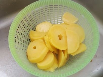 Kürbis-Kartoffel-Lauch-Gratin: Bringe in einem Topf leicht gesalzenes Wasser zum Kochen. Füge daraufhin die Kartoffelscheiben für ungefähr 5 Minuten hinzu und gieße sie anschließend in ein Sieb ab. 