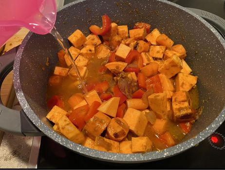 Rezept für eine Süßkartoffel-Kokos-Suppe: Lösche den Gemüse-Mix mit einem Liter Wasser oder Gemüsebrühe ab.
