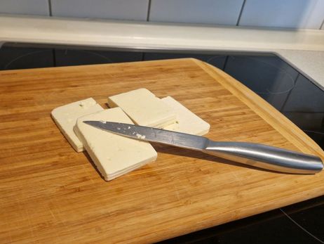 Rezept für ein paniertes Feta-Schnitzel mit Salat: Schneide den Käse in rechteckige Stücke.